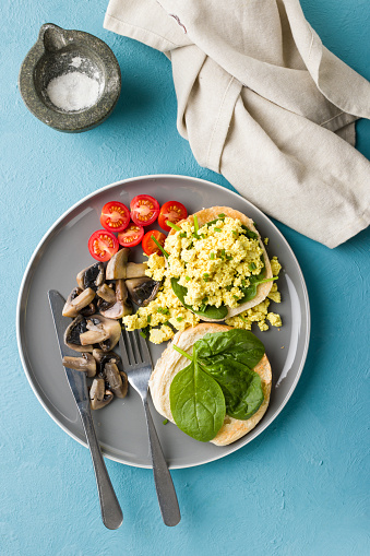 Homemade freshness scrambled tofu serves with English muffin, spinach and cherry tomato and sauté mushroom for breakfast
