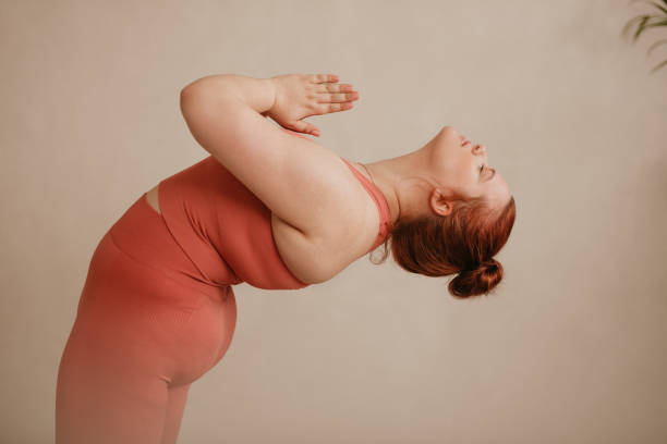 Healthy woman doing yoga exercise Strong woman with joined hands bending backward. Healthy woman doing yoga exercise in fitness studio. body positive stock pictures, royalty-free photos & images