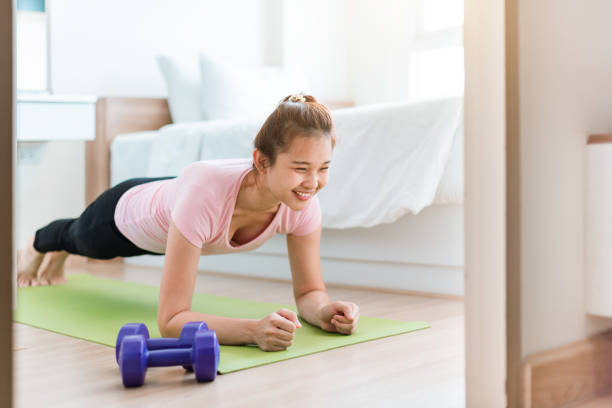 Healthy women  in sportswear clothes is doing a plank exercise on yoga mat in bed room. stock photo