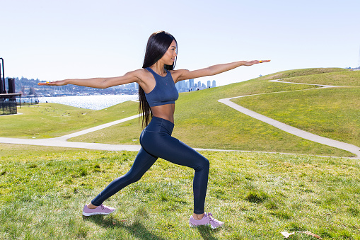 Pretty African American woman with black hair does yoga outside at Gasworks Park in Seattle, Washington, USA