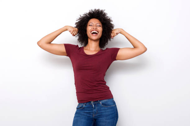healthy young african woman flexing both arms muscles on white background stock photo