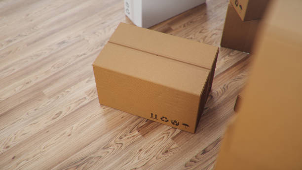 Heap of cardboard boxes for the delivery of goods, parcels, Cardboard boxes at home in a room on a wooden floor. Packages delivery, parcels transportation system concept, 3D illustration stock photo