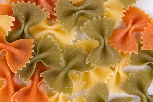A heap of tri color farfalle pasta. Close-up. Whole background. It occupies the entire surface of the image.