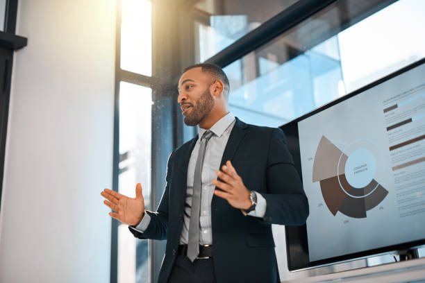 Hear me out on this one... Shot of a young businessman presenting data on a screen during a meeting in an office gesturing stock pictures, royalty-free photos & images