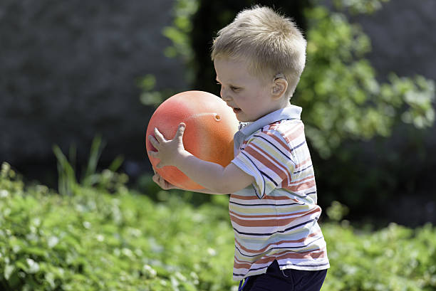 Hearing impaired boy playing ball stock photo