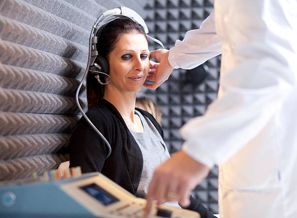 Hearing Test Woman getting a hearing test at a doctors office. tinnitus stock pictures, royalty-free photos & images