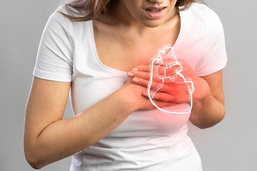 Young woman pressing on chest with painful expression. Severe heartache, having heart attack or painful cramps, heart disease.