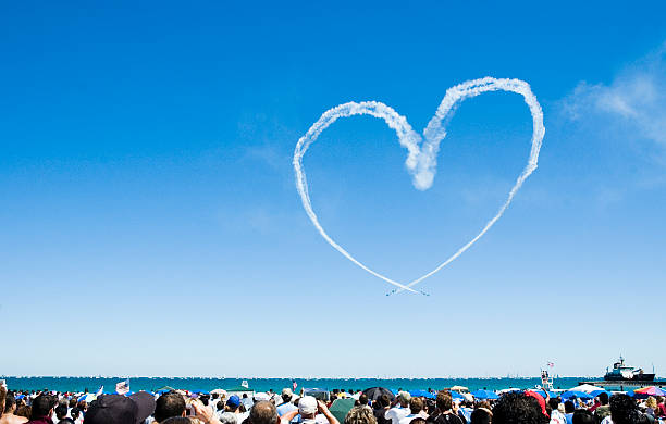 Heart made out of a planes smoke trail Biplanes make a heart in the sky as spectators watch from the beach.NEW: Video Version airshow stock pictures, royalty-free photos & images