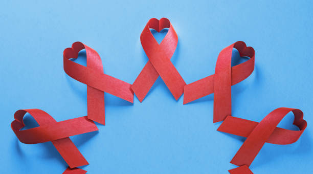 Heart Shaped AIDS Awareness Ribbons On Blue Background Heart shaped AIDS awareness ribbons are hand in hand on blue background. World AIDS awareness day concept. Horizontal composition with copy space. world aids day stock pictures, royalty-free photos & images