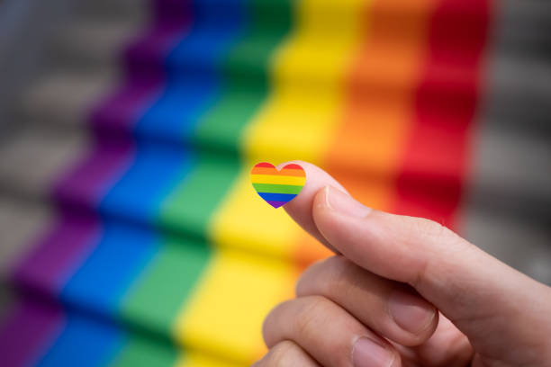 Heart shaped rainbow sticker in a hand for pride month celebration stock photo