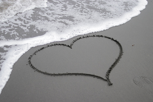 A heart symbol on the black sand beach with Soft Wave on the Background
