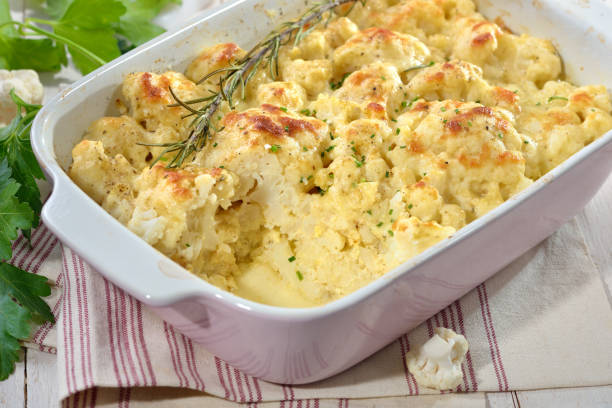 Hearty cauliflower gratin in a pink baking dish Hearty cauliflower gratin with eggs, natural yogurt and cheese freshly served from the oven gratin stock pictures, royalty-free photos & images