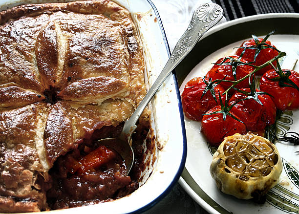 Hearty meat pie with roasted garlic & cherry tomatoes stock photo