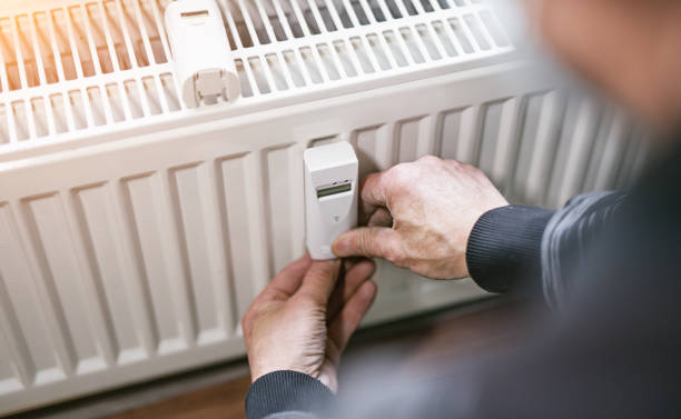 heating system engineer ist adjusting the digital w-lan network thermometer reader on a new thermal radiator. stock photo