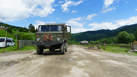 Heavy powerful old military green truck on country mountains road street. Horizontal long survival concept background.