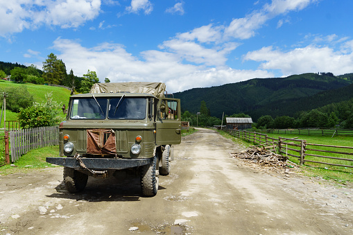 Heavy powerful old Soviet military green truck on country mountains road street. Horizontal survival concept background.