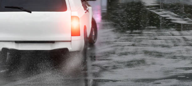 Heavy rain and puddles on the road cause skidding or sliding of a cars tires across a wet surface stock photo