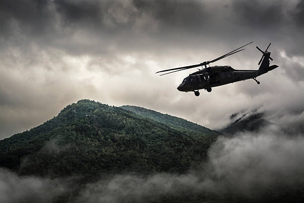 Helicopter Flying Over Mountain Surrounded by Fog stock photo