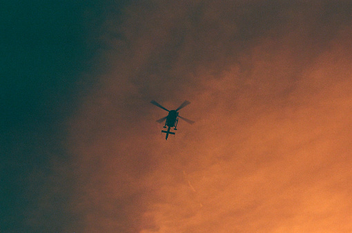 A helicopter flying directly above at sunset