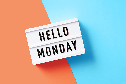 Hello Monday written white lightbox sitting on pink and blue background. Horizontal composition with copy space.