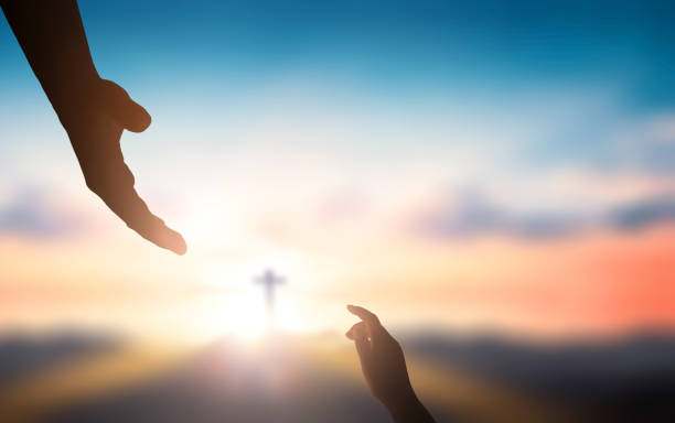 日の出の背景にぼやけた十字架の上に達する神の手を助ける 日の出の背景にぼやけた十字架の上に達する神のヘルプハンド - キリスト教 写真 ストックフォトと画像