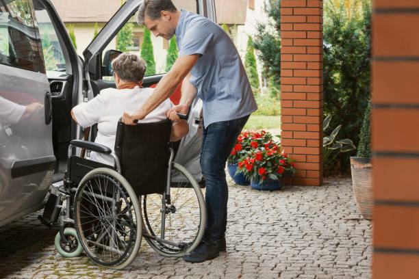 bra manliga sjuksköterska med äldre dam på rullstol hjälper henne att få in i bilen - transportmedel bildbanksfoton och bilder