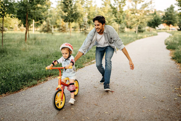 A helping hand Father teaching his daughter how to drive a bicycle riding stock pictures, royalty-free photos & images