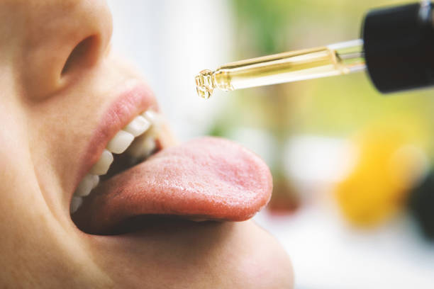 herbal alternative medicine and dietary supplements - woman taking cbd hemp oil drops in mouth from dropper. medical cannabis herbal alternative medicine and dietary supplements - woman taking cbd hemp oil drops in mouth from dropper. medical cannabis cbd oil stock pictures, royalty-free photos & images