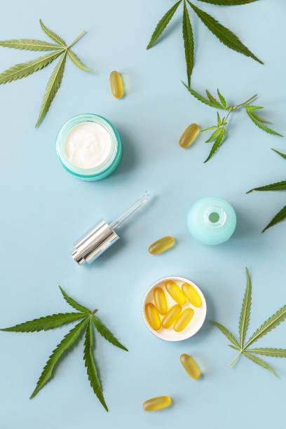 Herbal Alternative Medicine Concept, cosmetics CBD oil. Cannabis leaf skincare cosmetic product. Moisturizing cream, Serum, capsules oil on a pastel blue background. Top view flat lay. stock photo