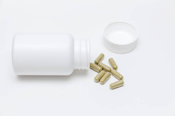 herbal capsules from bottle green capsules with vitamins from a white open bottle unmarked on a white background generic drug stock pictures, royalty-free photos & images