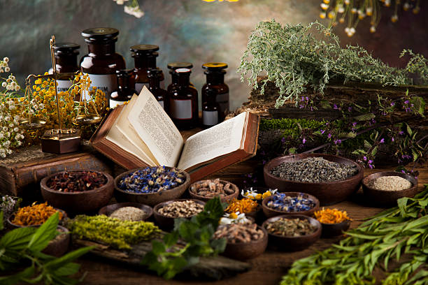 herbal medicine and book on wooden table background - alternatif tıp stok fotoğraflar ve resimler