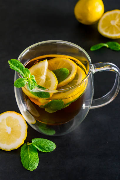 Herbal tea with lemon and mint on dark background. Delicious drink for relaxation and refreshment stock photo