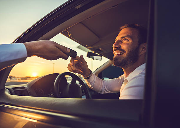 Here are your car keys! Happy businessman taking the car keys from unrecognizable person at sunset. car rental stock pictures, royalty-free photos & images