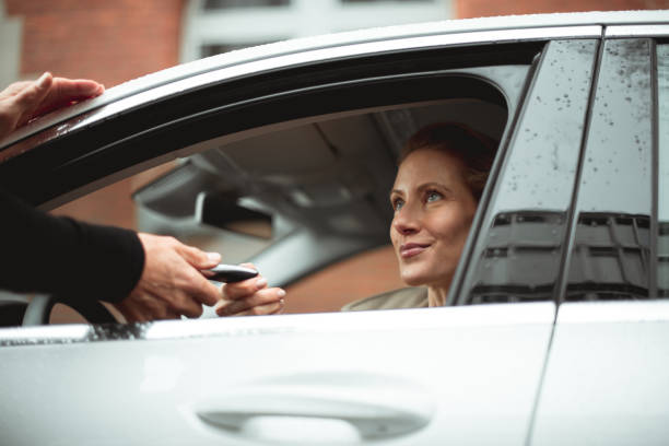 Here is your key Car rental dealer is giving a car key to a smiled caucasian woman who is sitting in the car. georgijevic frankfurt stock pictures, royalty-free photos & images