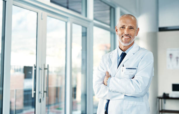 Here to keep you at your healthiest Portrait of a mature doctor standing in a hospital lab coat stock pictures, royalty-free photos & images