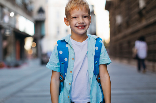 Portrait shot of a smiling young blond boy on the first day of school