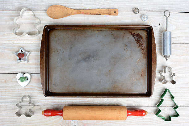 High Angle Baking Still Life Overhead shot of a group of items for baking Christmas Cookies surrounding an empty cookie sheet. Horizontal format on a  rustic wood kitchen table. baking sheet stock pictures, royalty-free photos & images