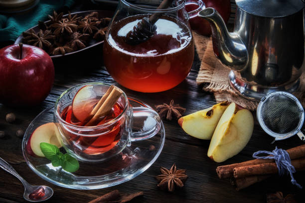 High angle close-up view of a cup of apple and cinnamon hot tea infusion on a table in a rustic kitchen stock photo