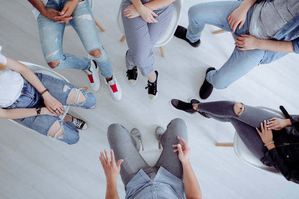High angle of teenagers meeting High angle of rehab specialist and rebellious teenagers sitting in the circle during meeting drug rehab stock pictures, royalty-free photos & images
