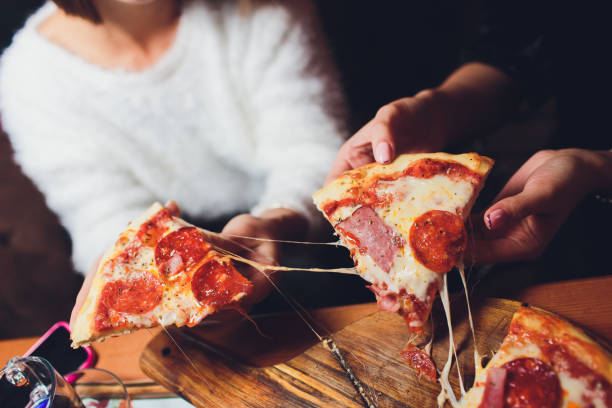 High angle shot of a group of unrecognizable people's hands each grabbing a slice of pizza. stock photo