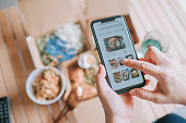 istock high angle view Close up Asian woman using meal delivery service ordering food online with mobile app on smartphone in the living room at a cozy home 1324465031