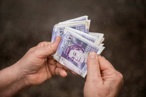 High angle view of an unrecognizable person holding group of twenty (20) pound notes stock photo