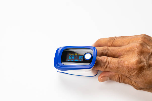 High angle view of doctor using pulse oximeter measured blood value of pulse rate and value of oxygen saturation at the finger tip of senior patient on white background stock photo