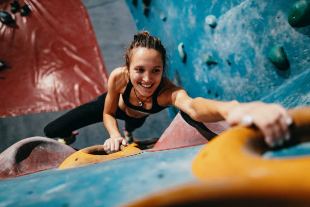 High angle view of skinny strong woman climbing on boulder wall Strong woman climbing on boulder wall bouldering stock pictures, royalty-free photos & images
