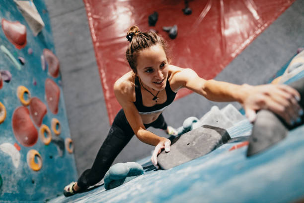 High angle view of strong woman on boulder climbing Strong woman practicing boulder climbing indoors bouldering stock pictures, royalty-free photos & images