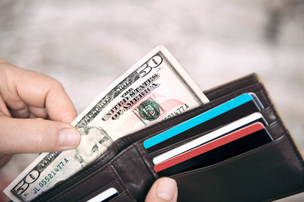 High angle view of unrecognizable mature man placing USA Dollar bills into wallet stock photo