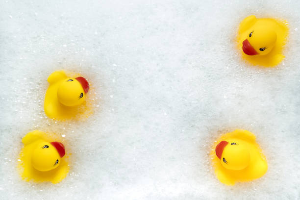 High Angle View of yellow rubber duck in bath swimming in foam water. Yellow rubber ducklings in soapy foam, fun for kids. stock photo
