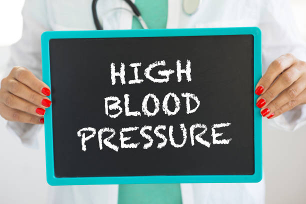 High blood pressure alert written with chalk on small blackboard held by doctor stock photo