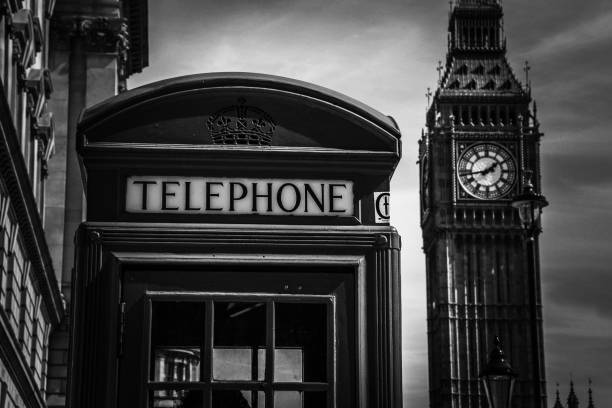 High contrast B&W photography of a British telephone box with the Elizabeth Tower, commonly known as Big Ben, at the Palace of Westminster in London, United Kingdom, in the background stock photo