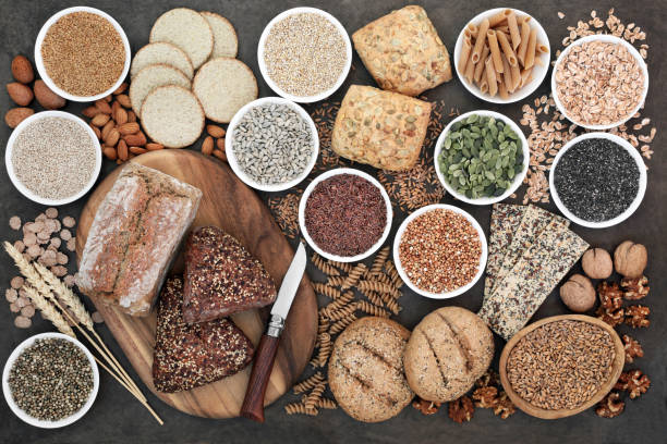 High Fibre Health Food High fibre health food with whole grain bread and rolls, whole wheat pasta, grains, nuts, seeds, oatmeal, oats, crackers, barley and bran flakes on lokta paper background. wholegrain stock pictures, royalty-free photos & images